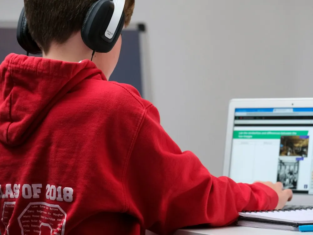 Estudante com fones de ouvido usando o notebook.